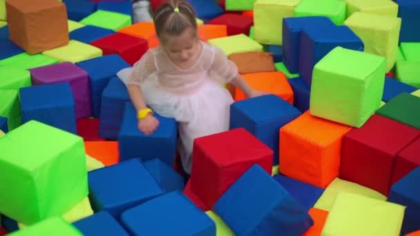 小さな赤ちゃんの女の子は柔らかいキューブドライプールゲーム誕生日のための子供部屋エンターテイメントセンター屋内遊び場泡ゴムピットトランポリン白人女性の子供 — ストック動画