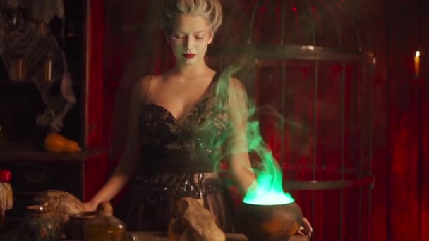 Halloween boszorkány üsttel. Gyönyörű fiatal nő varázsol, boszorkányságot csinál. — Stock videók