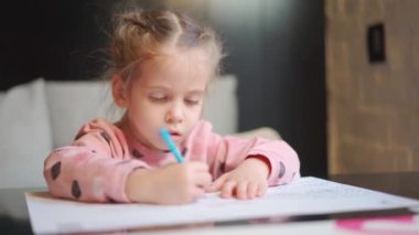 Çocuk çizimi masanın ortasında oturuyor. Beyaz kadın küçük kız renkli kalemlerle resim çiziyor. Ödev yapan kadın çocuk. 