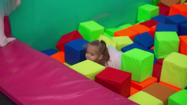 Mała dziewczynka bawiąca się miękkimi kostkami suchy basen gry pokój dla dzieci na urodziny Centrum rozrywki Kryty plac zabaw pianka guma pit trampolina kaukaska kobieta dziecko — Wideo stockowe