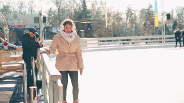 Молода усміхнена жінка катається на ковзанах на центральній міській площі на Різдвяних святах, активне зимове дозвілля в теплий сонячний день. Ручний ефект. аматорська біла жінка з льодом — стокове відео
