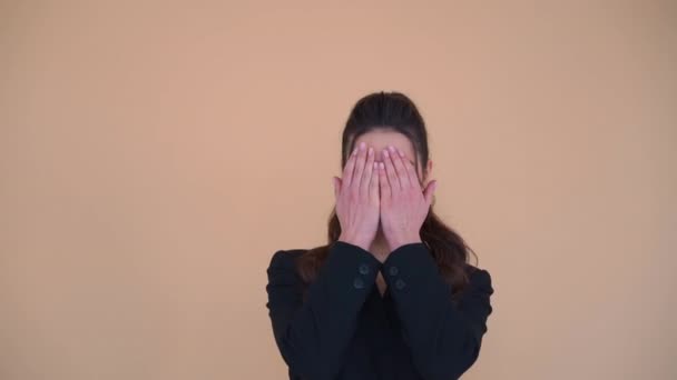 Mujer adorable feliz con el pelo moreno en chaqueta negra abriendo y cubriendo su cara con las manos, jugando a las escondidas, echar un vistazo a un gesto boo — Vídeo de stock