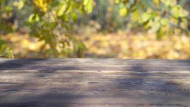 Mesa rústica de madera vieja al aire libre con hojas de otoño que caen en el fondo — Vídeos de Stock