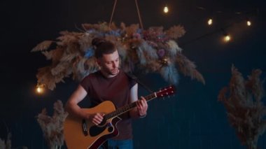 Erkek müzisyen akustik gitar çalıyor. Gitarist konserde sahnede klasik gitar çalar.