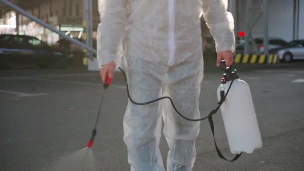 Beyaz elbiseli bir adam karantina sırasında yüzey antibakteriyel dezenfektan püskürtüyor. — Stok video