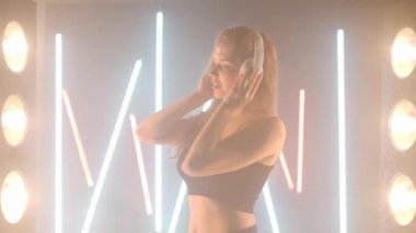 Kulaklık takan sanatçı genç bir kadın arka plandaki sis dumanında dans etmekten zevk alıyor. Kendine güvenen zarif beyaz kadın dansçı modern performans.