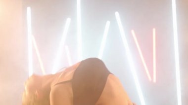 Arka planda sis dumanı içinde dans eden sanatçı genç bir kadın. Kendine güvenen zarif beyaz kadın dansçı modern performansı bale hareketleri ile prova ediyor.