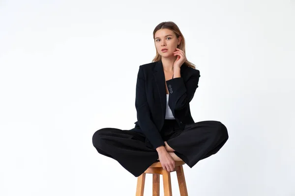 若いファッショナブルなビジネス女性高バー木製の椅子蓮の位置に座って白い背景に隔離された黒のオフィススーツを着て 白人女性ビジネスパーソン瞑想コンセプト — ストック写真