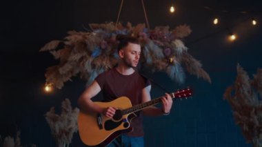Erkek müzisyen akustik gitar çalıyor. Gitarist konserde sahnede klasik gitar çalar.