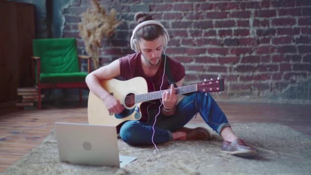 Man akoestische gitaar zithoek met laptop en koptelefoon spelen zang lied online muziek lessen — Stockvideo