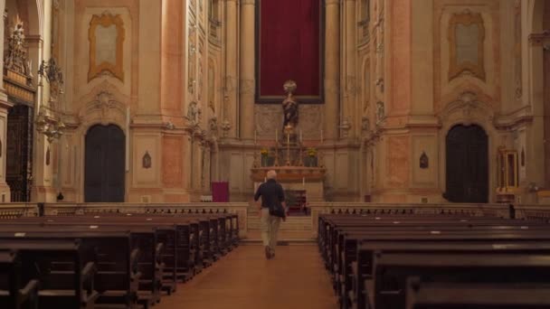 Homem idoso entra na igreja, visão traseira. Igreja Católica dentro da oração da noite, atmosfera mística escura Homem sentado banco na Igreja e meditando, fé e religião — Vídeo de Stock