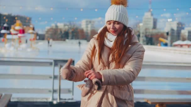 Молода усміхнена жінка катається на ковзанах на центральній міській площі на Різдвяних святах, активне зимове дозвілля в теплий сонячний день. Ручний ефект. аматорська біла жінка з льодом — стокове відео