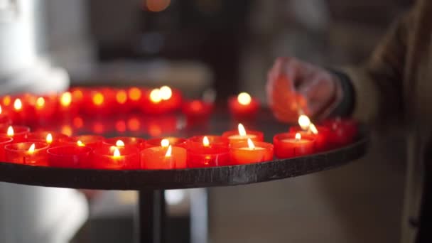 Detalhe fechar homens mão acender velas com cuidado em uma igreja católica — Vídeo de Stock