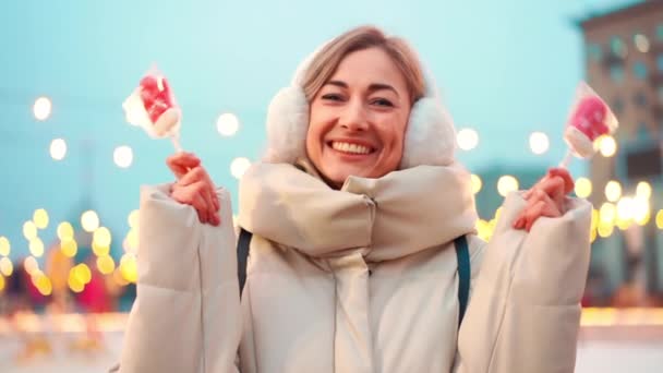 Mujer alegre de mediana edad disfruta del frío invierno Navidad vacaciones invierno de pie calle de la ciudad mercado estacional y la guirnalda ligera de Navidad en el fondo — Vídeos de Stock
