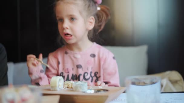 Barn äter sashimi på restaurang. Mellanslag liten flicka äter sushi och sashimi inomhus. Kaukasiska kvinnliga barn provsmakning japanska köket — Stockvideo