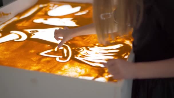 Анімація піску, жіноча рука малює на світлій коробці для столу з піском. Освіта живопис на піску . — стокове відео