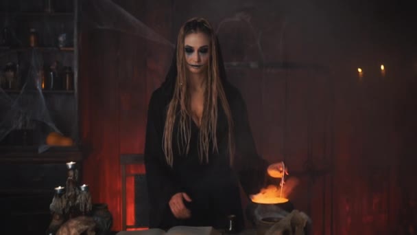Halloween, bruja utilizar el libro de magia y caldero preparar veneno o poción de amor — Vídeo de stock