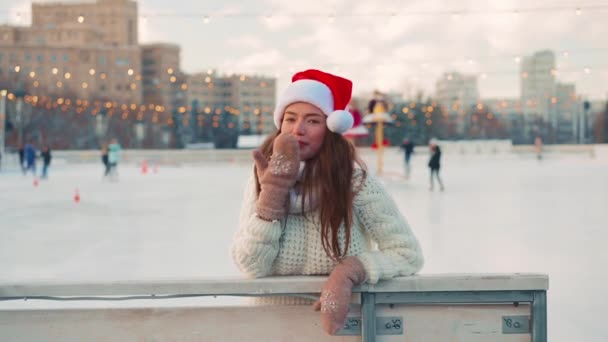 Joven mujer sonriente Santa sombrero patinaje sobre hielo fuera en pista de hielo vestido suéter blanco. Vacaciones de Navidad, ocio activo de invierno Efecto de mano. Amateur caucásico hembra patinador de hielo — Vídeos de Stock