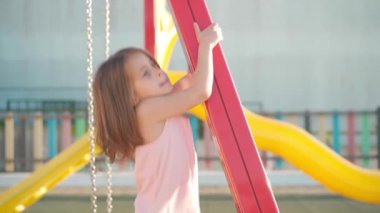 Çocuk sıcak yaz gününde oyun parkında oynuyor. Küçük kız eğleniyor. Mutlu çocukluk. 