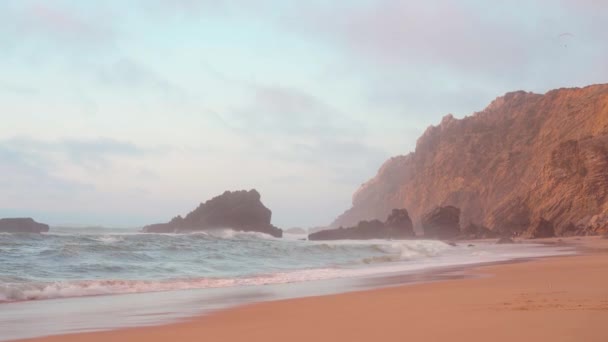 Океан дикого пляжа штормовая погода. Прайя-да-Адрага песчаный пляж с живописным пейзажем, Синтра-Кашкайш, Португалия — стоковое видео