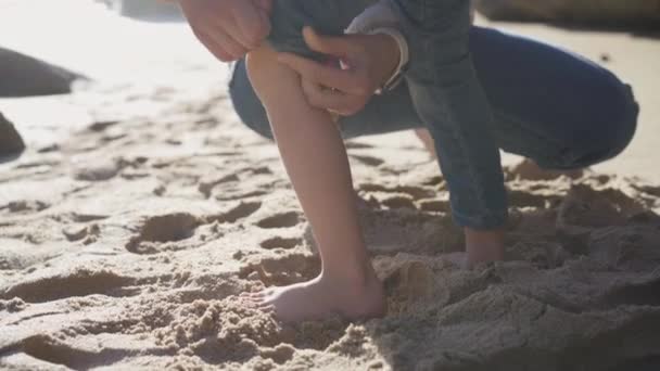 Anne kızının pantolonunu sıyırmasına yardım eder, böylece plaj boyunca koşar ve elbiselerini ıslatmaz. — Stok video