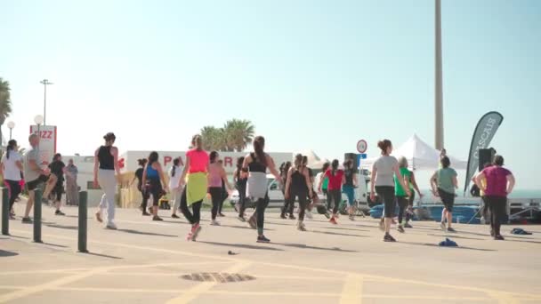 Portugal, Lissabon april 2022 Carcavelos Beach Group fitnesslessen. Opleiding aan de dijk. Buitensporten. Veel mensen doen fitness oefeningen. Wellness lifestyle concept — Stockvideo