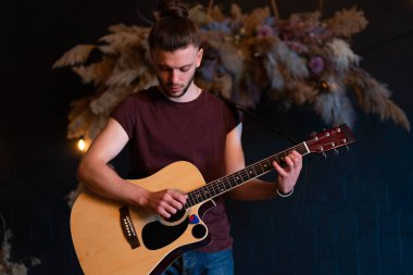 Erkek müzisyen akustik gitar çalıyor. Gitarist konserde klasik gitar çalıyor. Yakışıklı genç hippi gitarist özel bir parti veriyor. Uzun saçlı, orta boy.