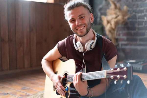 Akustik gitar çalan yakışıklı genç adam oturma odasında beyaz tenli erkek hippi kulaklıkçı şarkı söyleyen, müzik dinleyen, yaratıcı, genç adamı rahatlatan, orta yaşlı adam.