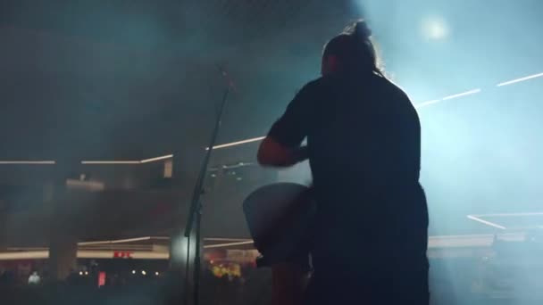 Hombre tocando tambores étnicos de pie en el escenario en humo y focos — Vídeos de Stock