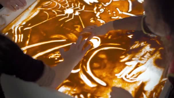 Анімація піску, жіноча рука малює на світлій коробці для столу з піском. Освіта живопис на піску . — стокове відео