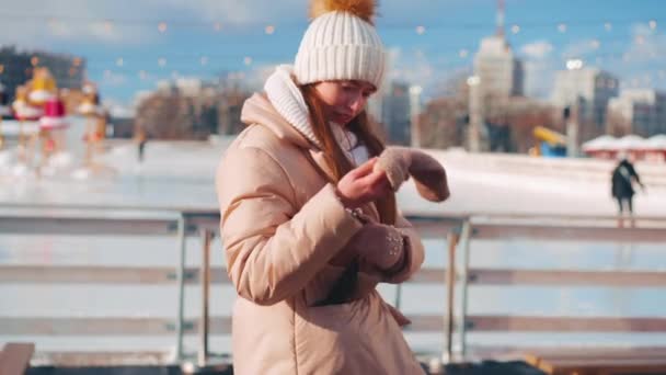 Jovem sorrindo mulher patinação no gelo do lado de fora na pista de gelo praça central da cidade nas férias de Natal, lazer de inverno ativo no dia ensolarado quente. Efeito portátil. Amador caucasiano feminino patinadora no gelo — Vídeo de Stock