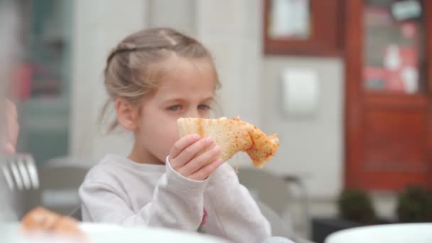 Ładna mała dziewczynka kaukaski jedzenie pizzy. Głodne dziecko biorąc bite od pizzy. — Wideo stockowe