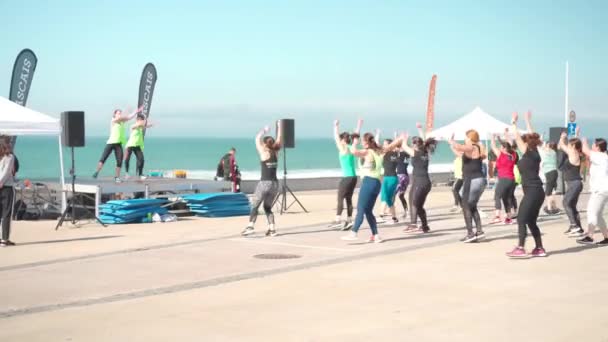 Portugal, Lisbon April 2022 Carcavelos Beach Group fitness classes. Training on embankment. Outdoor sports. Many people do fitness exercises. Wellness lifestyle concept — Stockvideo