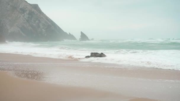 Океанський дикий пляж штормову погоду. Піщаний пляж Praia da Adraga з мальовничим ландшафтним тлом Sintra Cascais, Portugal — стокове відео