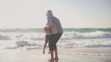Anne ve çocuk baharda okyanus kumsalında oynuyorlar, çıplak ayakla çıplak ayakla video efekti giyiyorlar.
