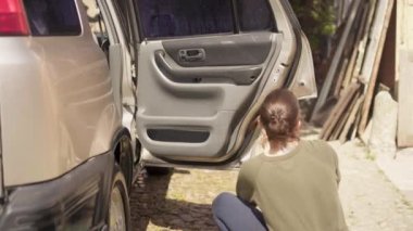 Kadın evinin yakınındaki avlusunda şampuan ve bez ile araba yıkıyor. Kafkasyalı kadın evinin yakınında süngerle araba yıkıyor.