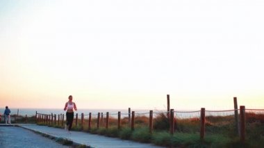 Koşucu Kadın Okyanus yakınında Sunny Yolu 'nda koşuyor. Sporcu Kadın Akşam Koşusu Eğitimi Sunset 'te. Sağlıklı yaşam tarzı. Dikkatli Koşu, Yavaş Çekim Tutucu.