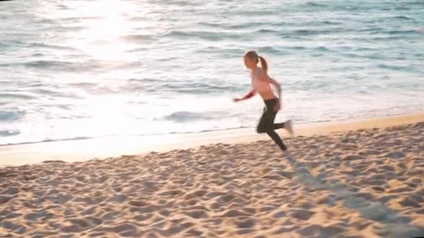 Deportiva mujer rubia corriendo playa del océano. Joven hembra caucásica haciendo ejercicio al aire libre corriendo por la orilla del mar. Concepto de correr sano y ejercicio al aire libre. — Vídeos de Stock