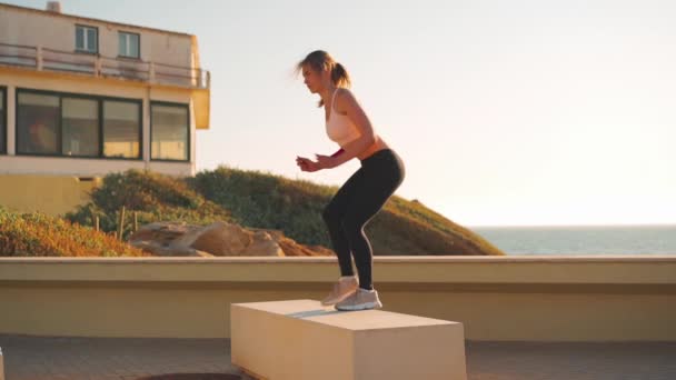 Slim fitness femenino step-up caja de salto de ejercicio, fortalecimiento y tonificación de cuádriceps e isquiotibiales mientras practica el entrenamiento cruzado en el gimnasio al aire libre. — Vídeo de stock