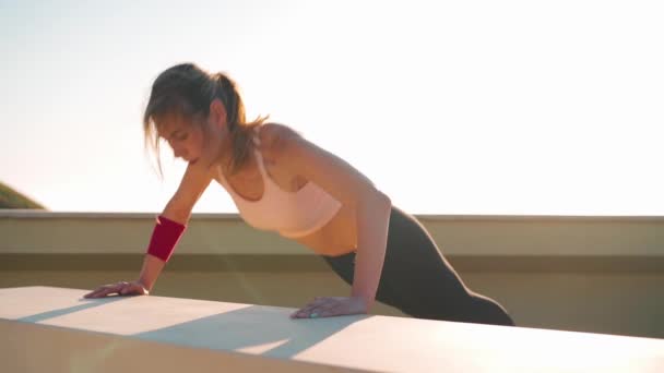 Fit sportieve vrouw doet plank buiten. Gespierde vrouwelijke sport outfit doen workout. Avondbeelden bij zonsondergang aan de kust. — Stockvideo