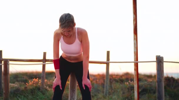 Kvinna löpare magert knä medan du tar paus på vacker solnedgång bakgrund. Kaukasisk kvinnlig joggare vilar efter kvällsträning stående klädda sportkläder. — Stockvideo