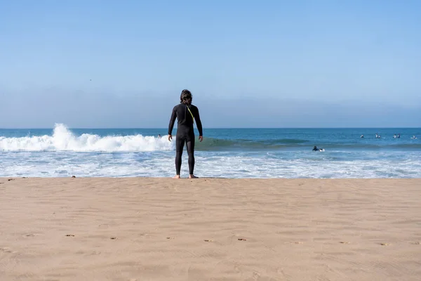 Een Man Gekleed Zwart Wetsuit Staande Oceaan Strand Achteraanzicht Kijken — Stockfoto