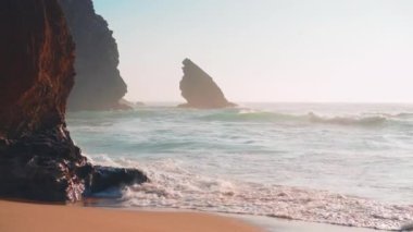 Okyanus vahşi kumsal fırtınalı havası. Praia da Adraga kumlu plajı manzaralı arka plan, Sintra Cascais, Portekiz el bilgisayarı etkisi. Mavi enerjinin ve berrak okyanus suyunun canlılığı