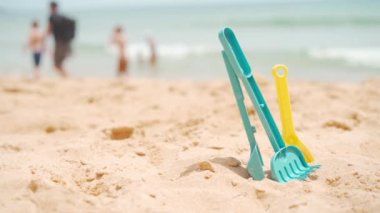 Plastik plaj oyuncakları sahile yakın kumda. Mesaj için yer var. Plajda oynayan çocuklar için plastik oyuncaklar. Bulanık okyanus sahili geçmişinde insanlarla