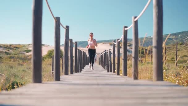 Sportlerin Läuft Auf Holzweg Strand Zeitlupe Tracking Schuss Entzückende Junge — Stockvideo