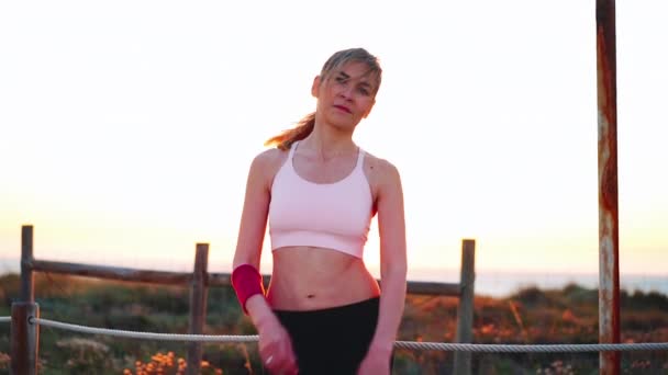 女跑步者在美丽的日落背景下休息 白种人的女慢跑者在晚上锻炼后 穿着运动服站着休息 健康生活方式概念 — 图库视频影像