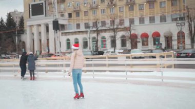 Kış zamanı. Mutlu kadın buz pateni pistinde vakit geçiriyor. Noel tatili, Santa Şapkalı kadın Central City meydanında buz pateni pistinde. Kış tatili. 35 yaşında kadın.