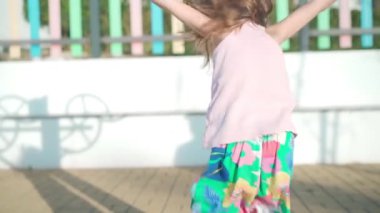 Çocuk sıcak yaz gününde oyun parkında oynuyor. Küçük kız eğleniyor. Mutlu bir çocukluk. Kafkasyalı küçük kız 5 yıldır dışarıda baş aşağı asılı oynuyor.