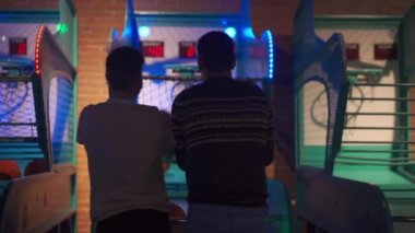 İnsanlar alışveriş merkezindeki Oyun Alanındaki Arcade Machine 'de basketbol oynayıp top atıyorlar. Tanınmayan iki kişi oyun makinesiyle iyi eğlenceler.