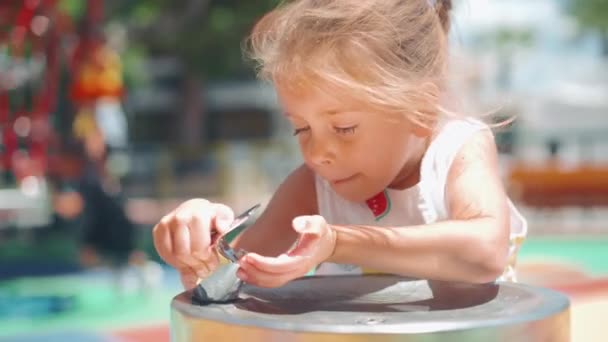 Dziewczynka Pije Strumień Wody Fontanną Zdekoncentrowanymi Dziećmi Placu Zabaw Tle — Wideo stockowe